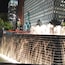 Une cascade illuminée la nuit, avec une statue en arrière-plan.