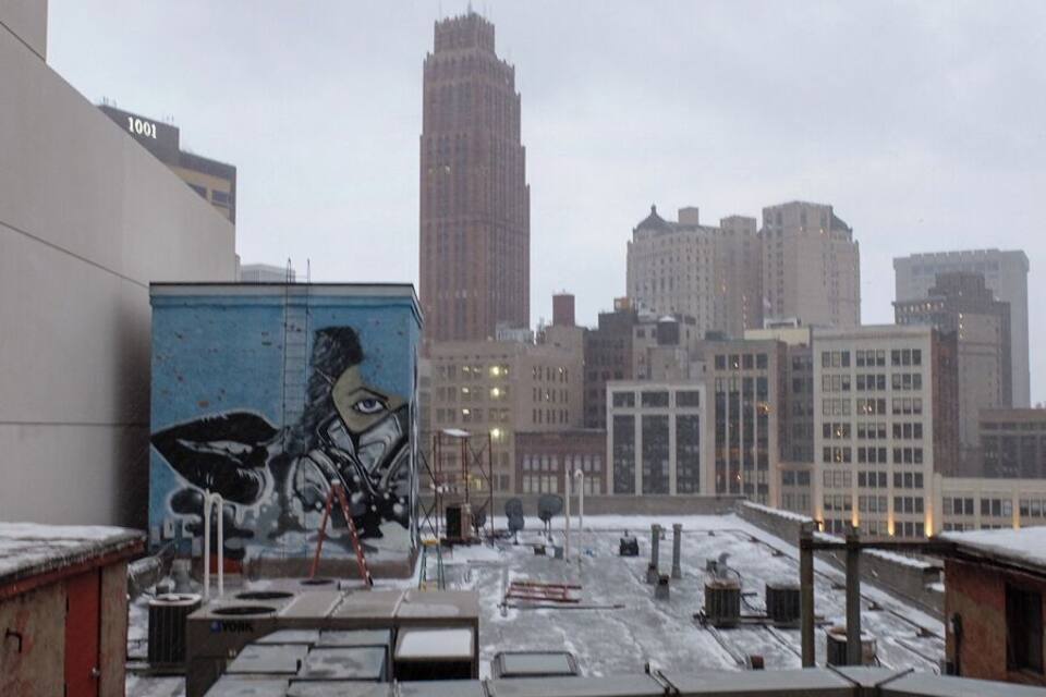 Une vue urbaine avec un grand immeuble en arrière-plan et une fresque murale sur un bâtiment au premier plan.