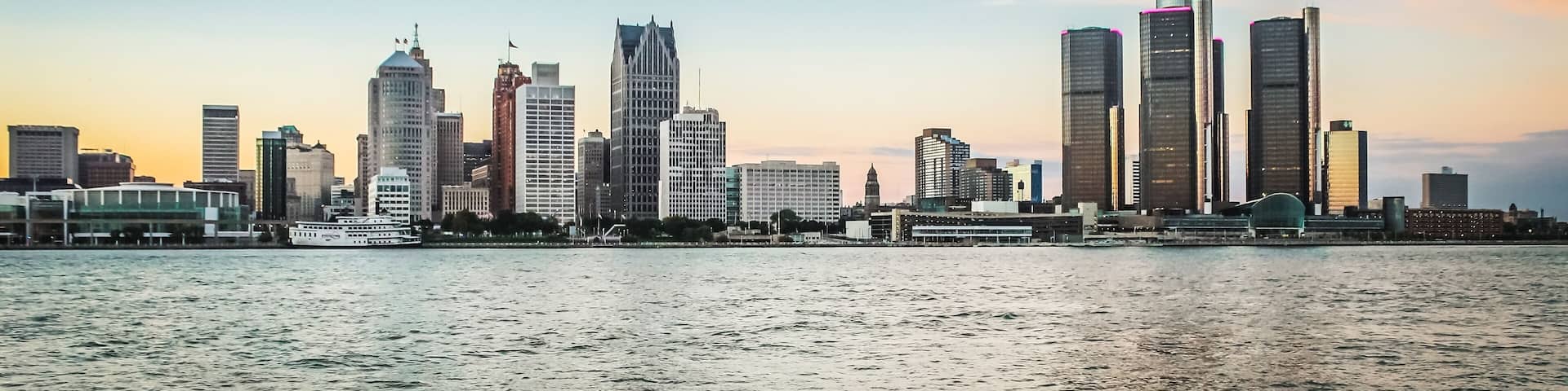 A city skyline with tall buildings and a body of water in the foreground.