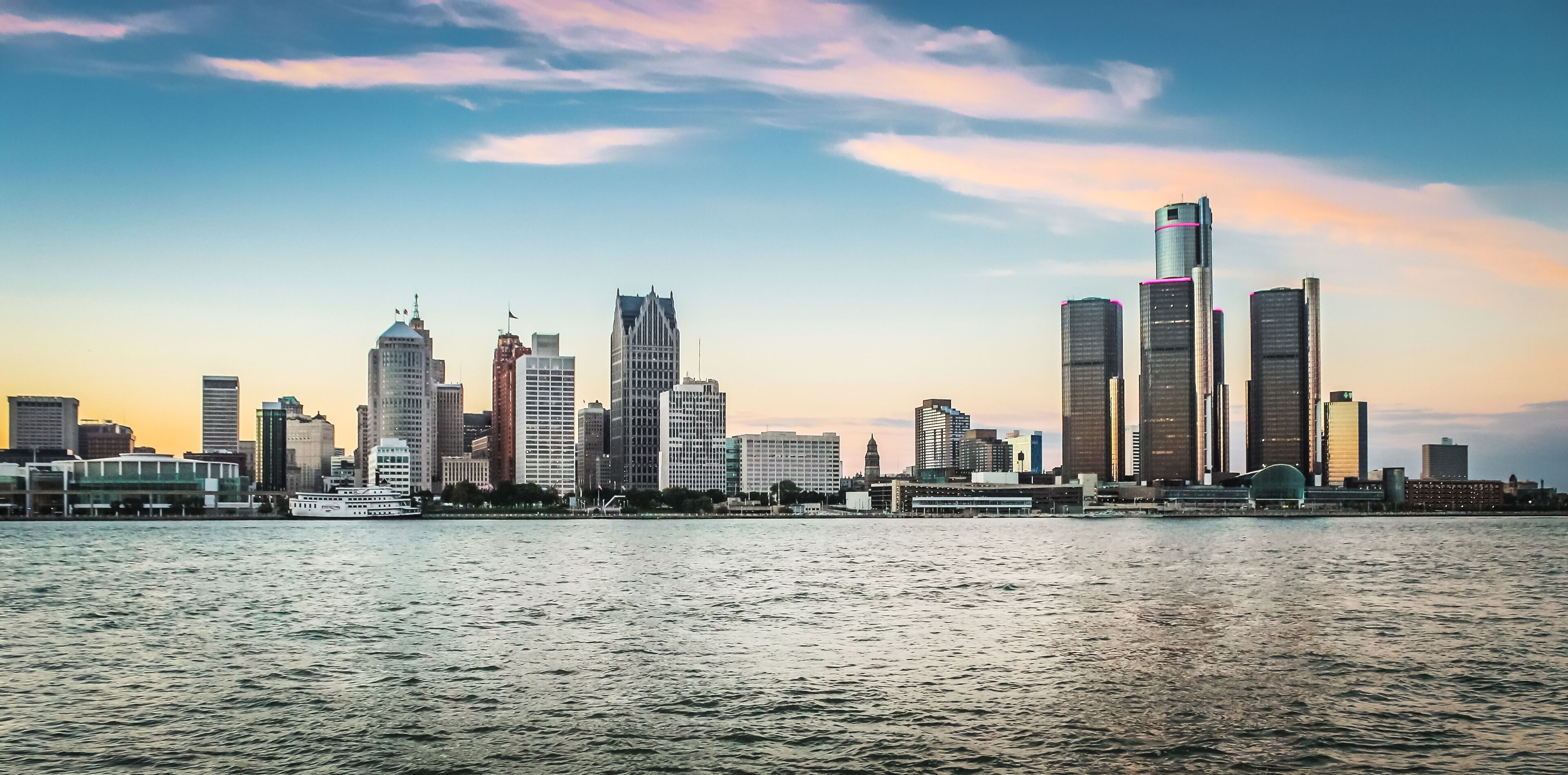 A city skyline with tall buildings and a body of water in the foreground.
