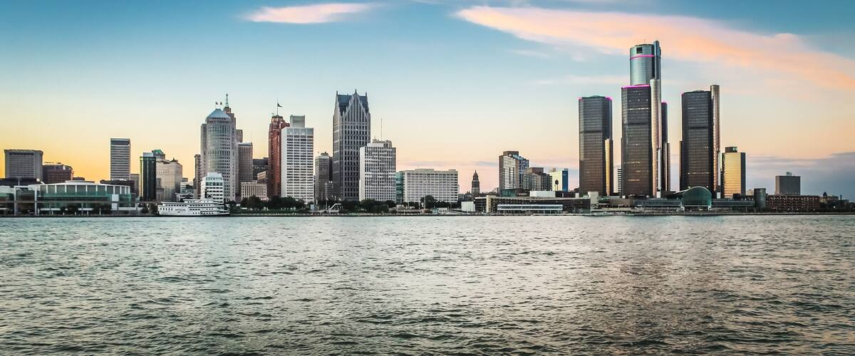A city skyline with tall buildings and a body of water in the foreground.
