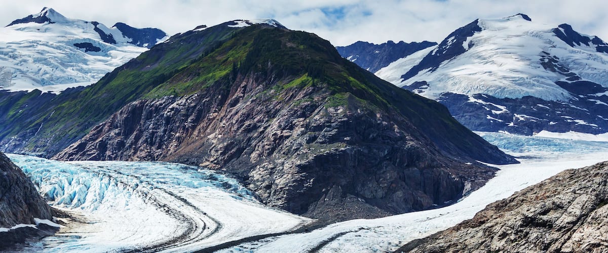 Um glaciar com montanhas rochosas imponentes ao fundo.