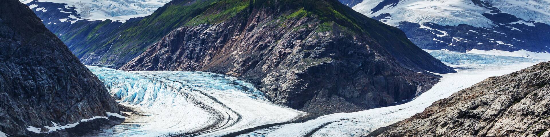 A glacier with steep, rocky mountains in the background.