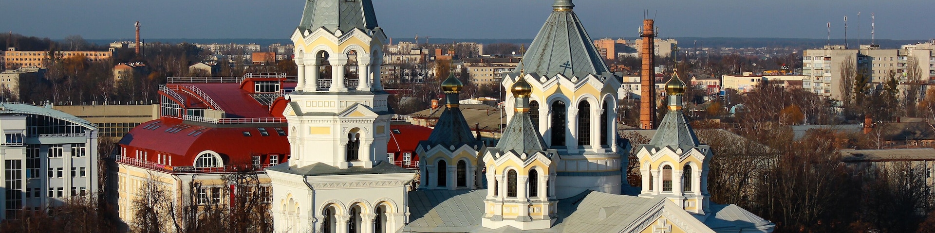 Uma igreja histórica com várias torres e cúpulas, rodeada por edifícios urbanos.