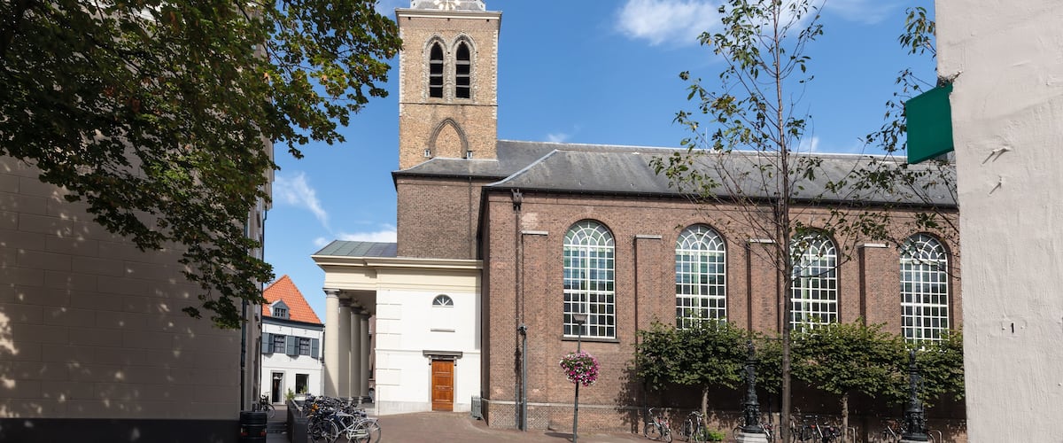 A historic building with a clock tower, brick walls, and arched windows.