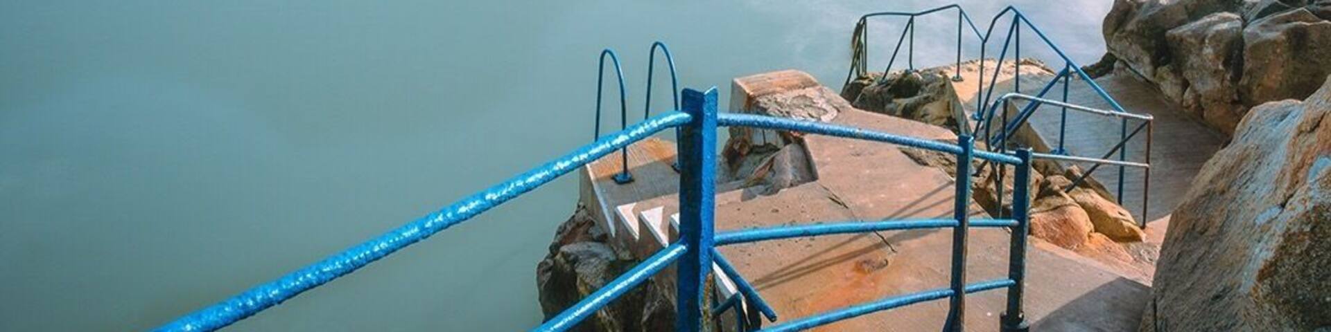 A coastal viewpoint with a stone staircase leading to a rocky platform overlooking the sea.