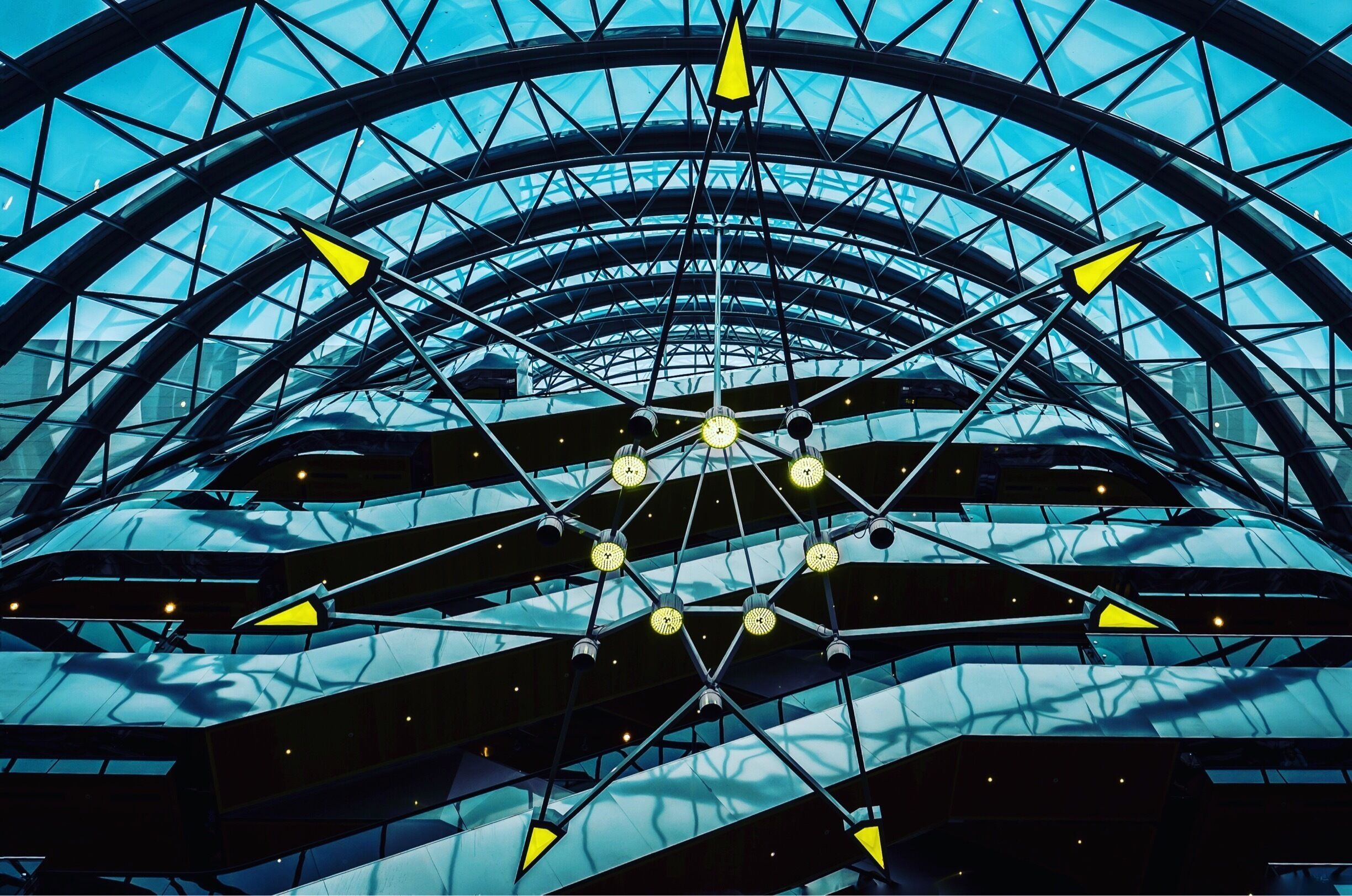 A modern architectural structure with a glass dome and intersecting steel beams.