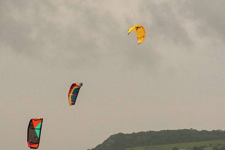 A coastal area with waves and kitesurfers.