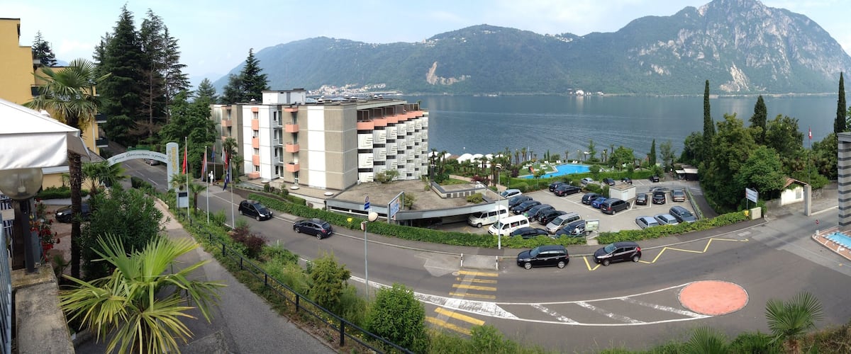 A coastal road with a parking lot, a swimming pool, and a mountain in the background.