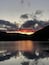 Un atardecer sobre un lago tranquilo, con montañas al fondo.