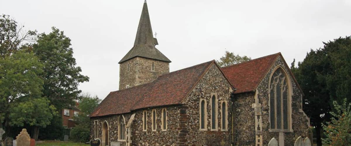 A stone church with a tall steeple and a large arched window.