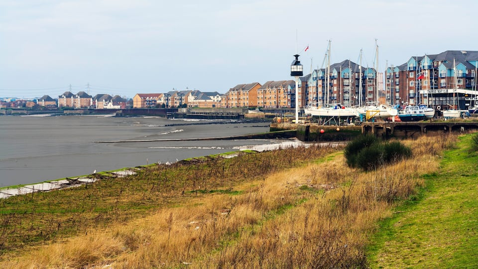A waterfront with boats, a pier, and a row of colorful buildings.