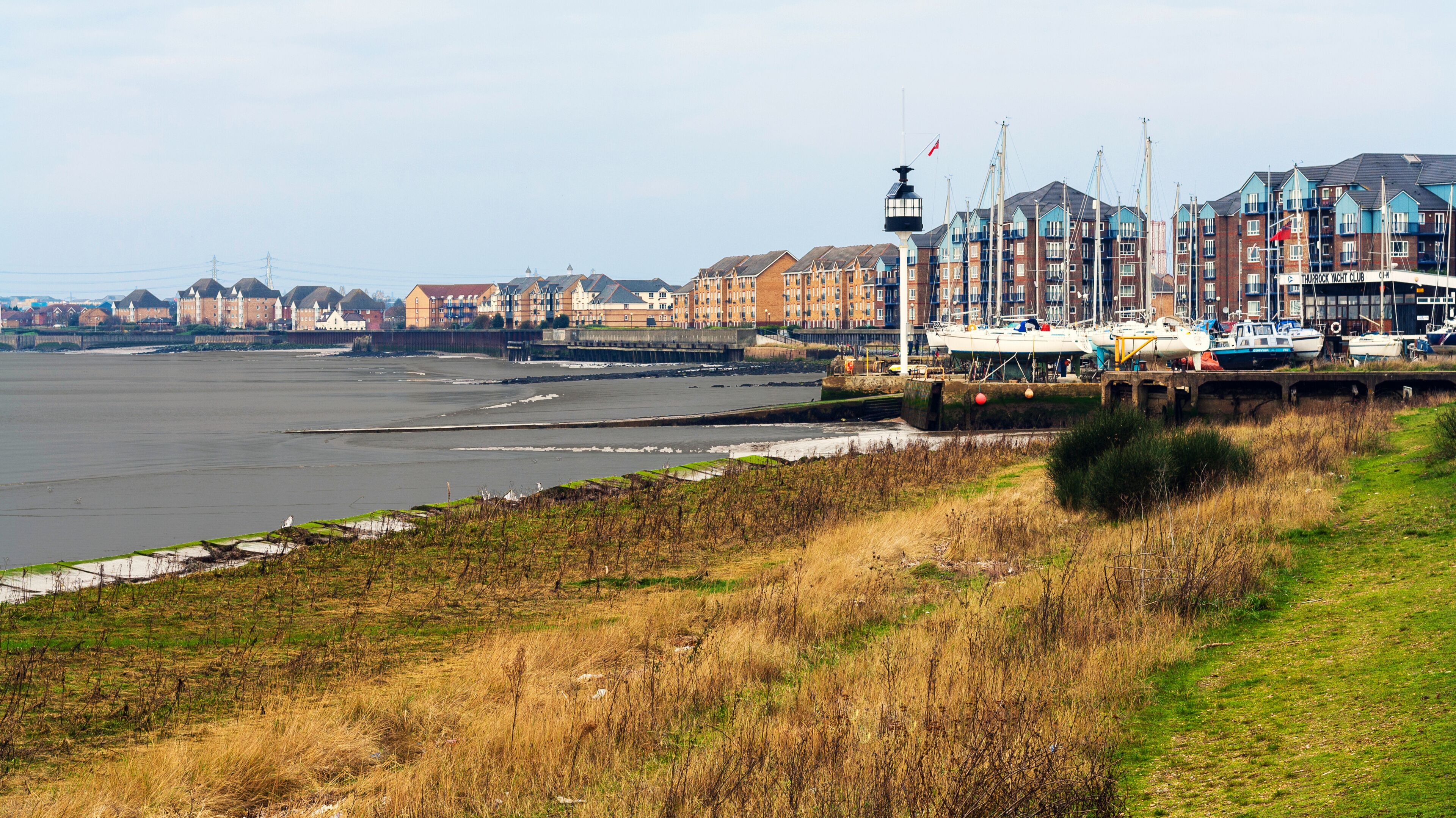 A waterfront with boats, a pier, and a row of colorful buildings.