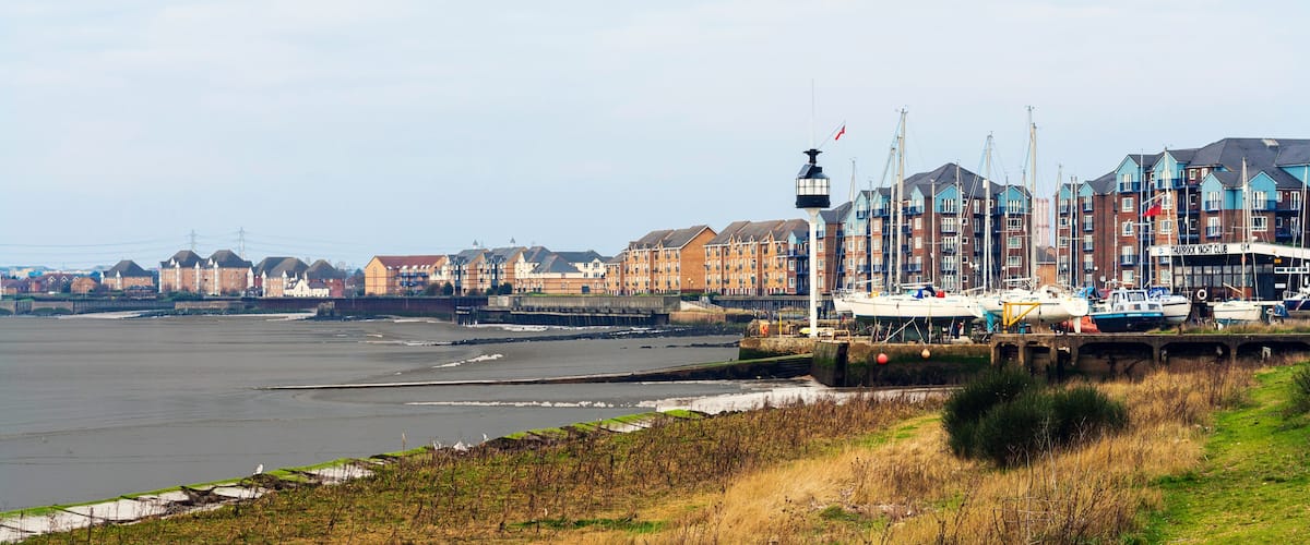 A waterfront with boats, a pier, and a row of colorful buildings.