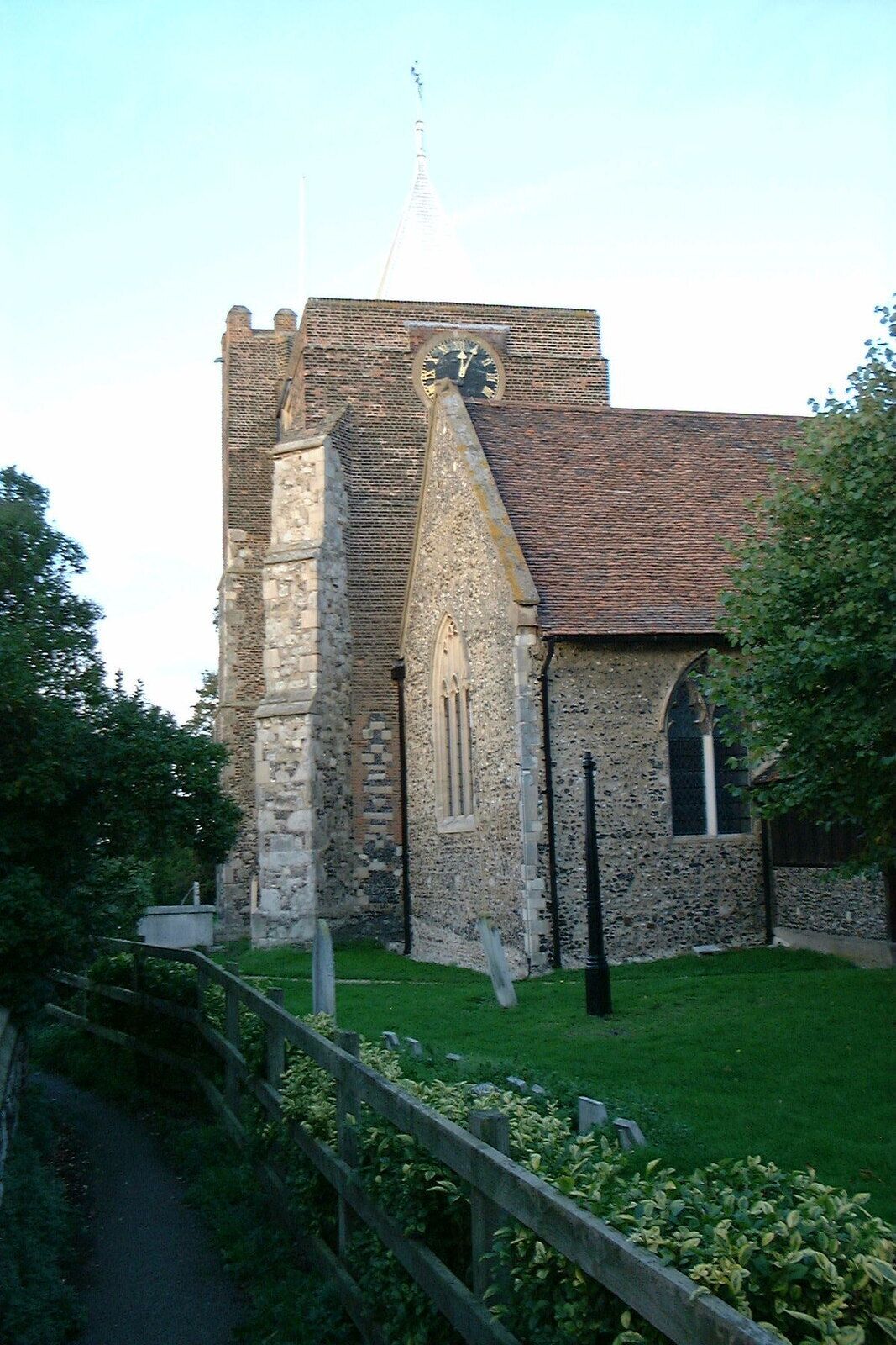 A historic church with a clock tower, stone walls, and a grassy courtyard.
