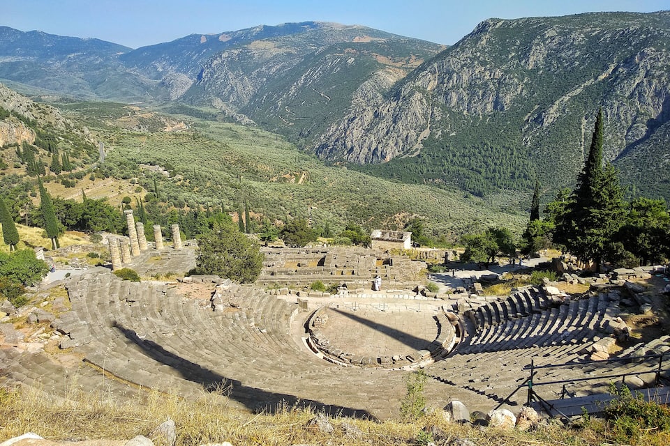 Un amphithéâtre antique, entouré de montagnes et de verdure.