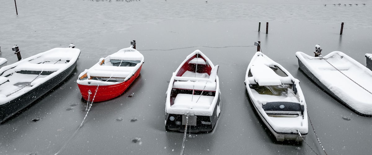 A row of boats tied to a dock in a snowy landscape.