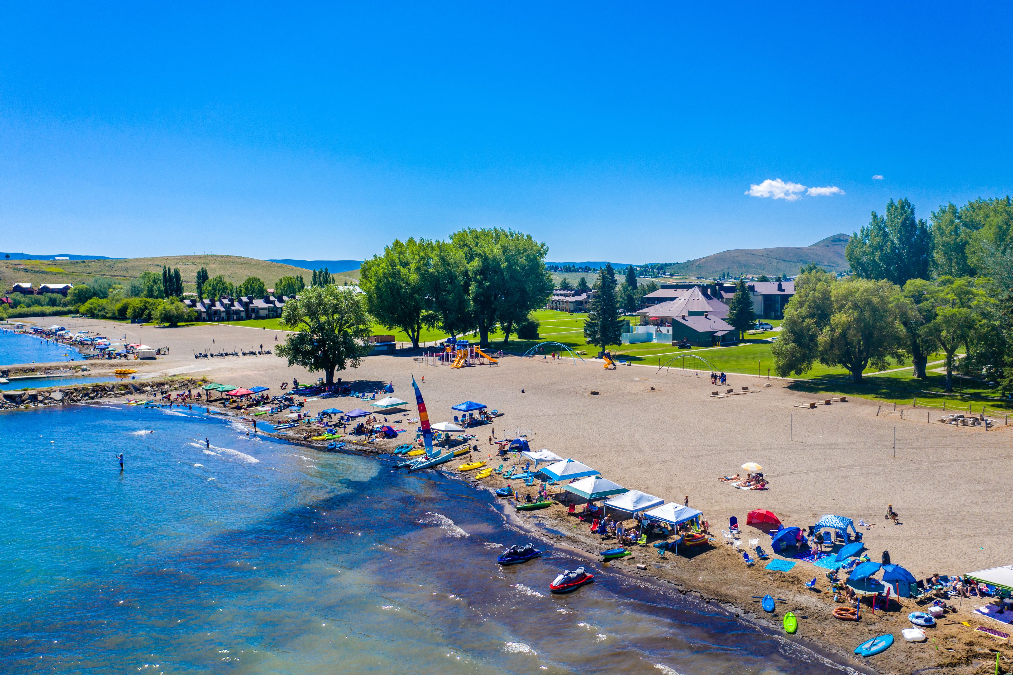 Una spiaggia con acque cristalline blu, una battigia sabbiosa e alcune imbarcazioni.