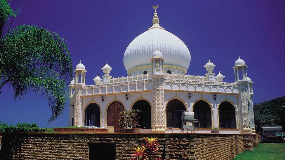 A white domed building with arched windows and a crescent moon on top.