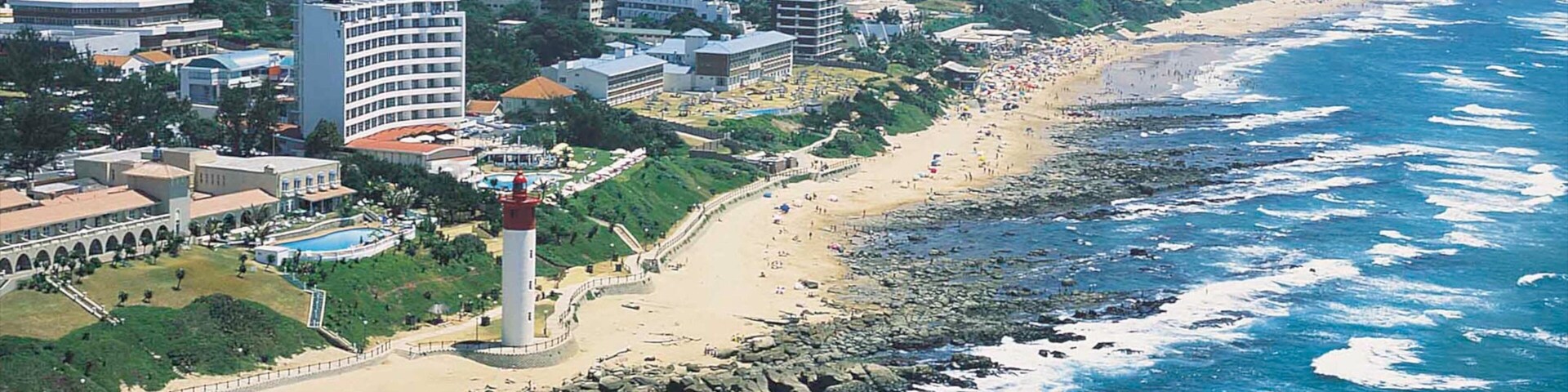 Uma cidade costeira com praia, litoral rochoso e edifícios altos.