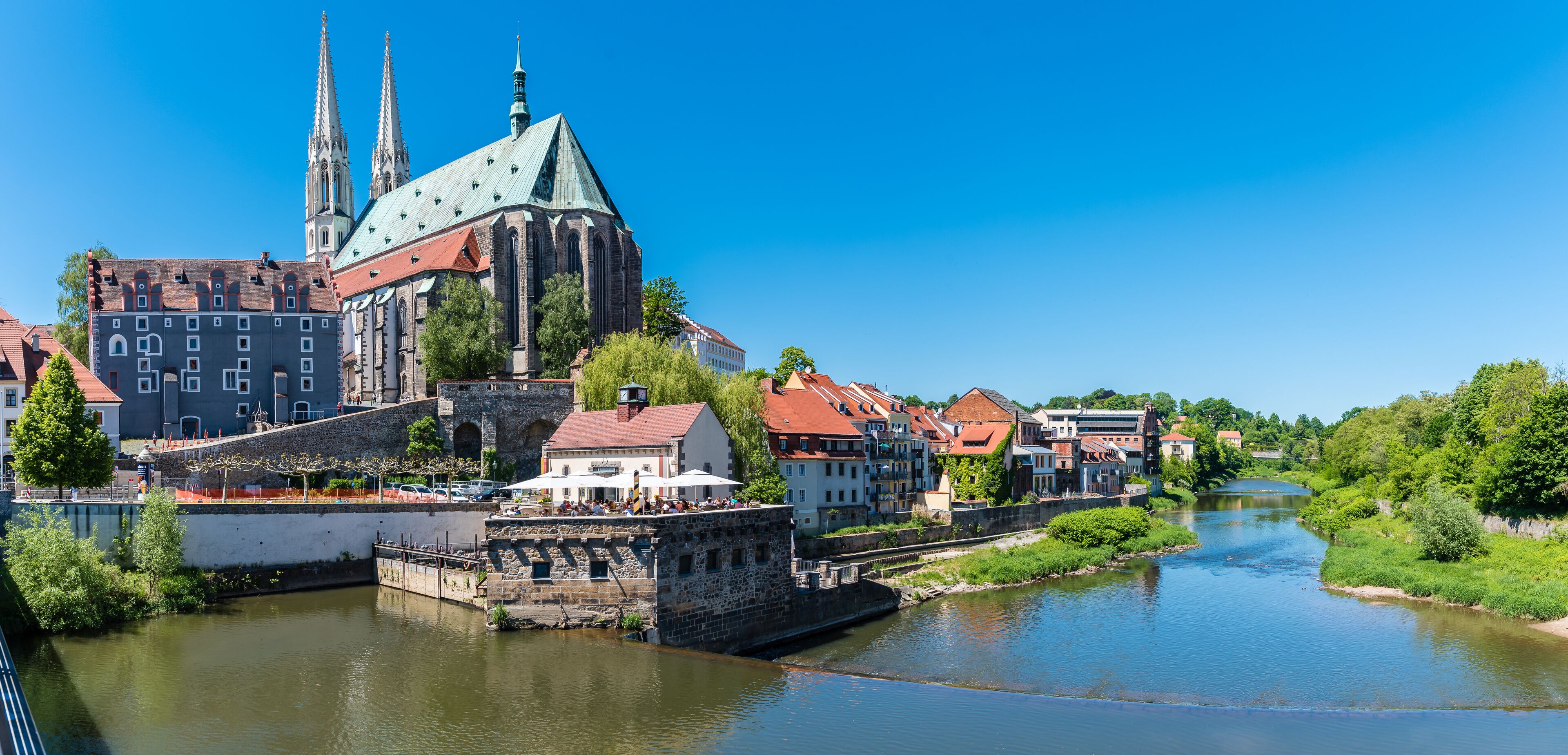 Eine historische Stadt mit einem markanten Kirchengebäude, einem Fluss und umgebender Natur.