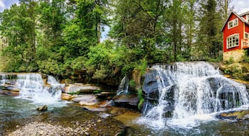 A waterfall, a river, and a red house with a wooden deck.