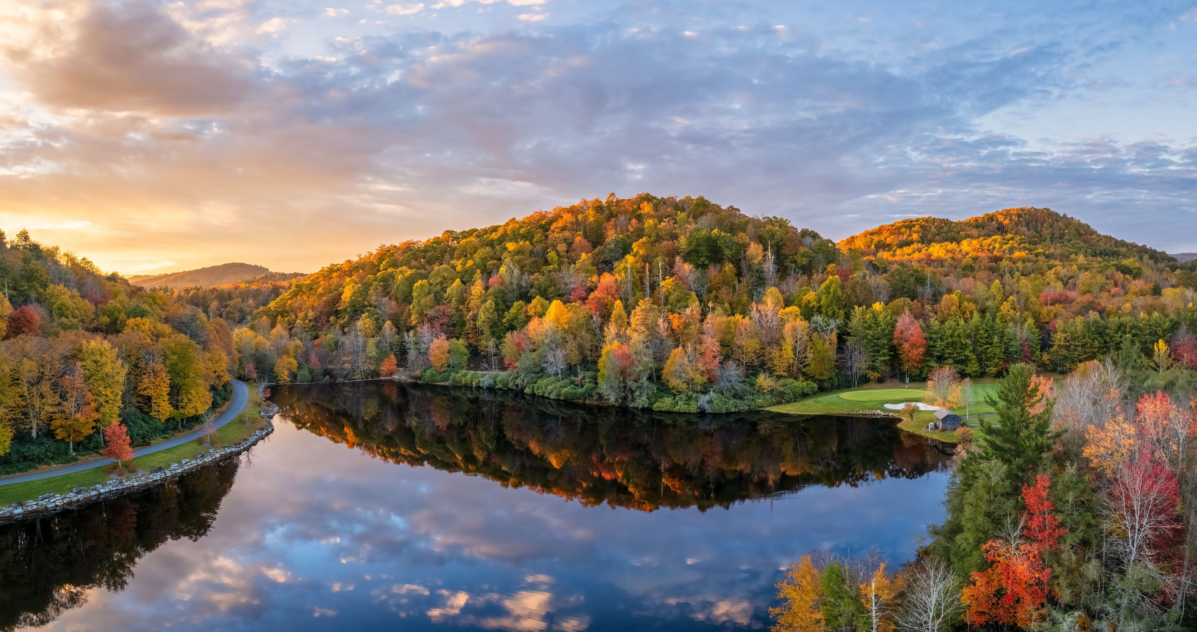 A serene lake surrounded by autumn-colored trees and hills.