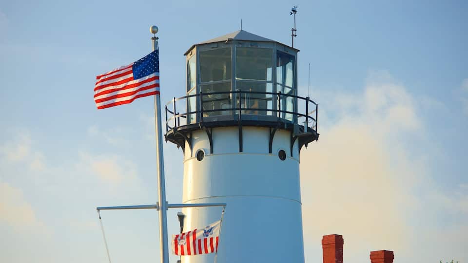 A lighthouse with an American flag and a smaller flag with a blue eagle.