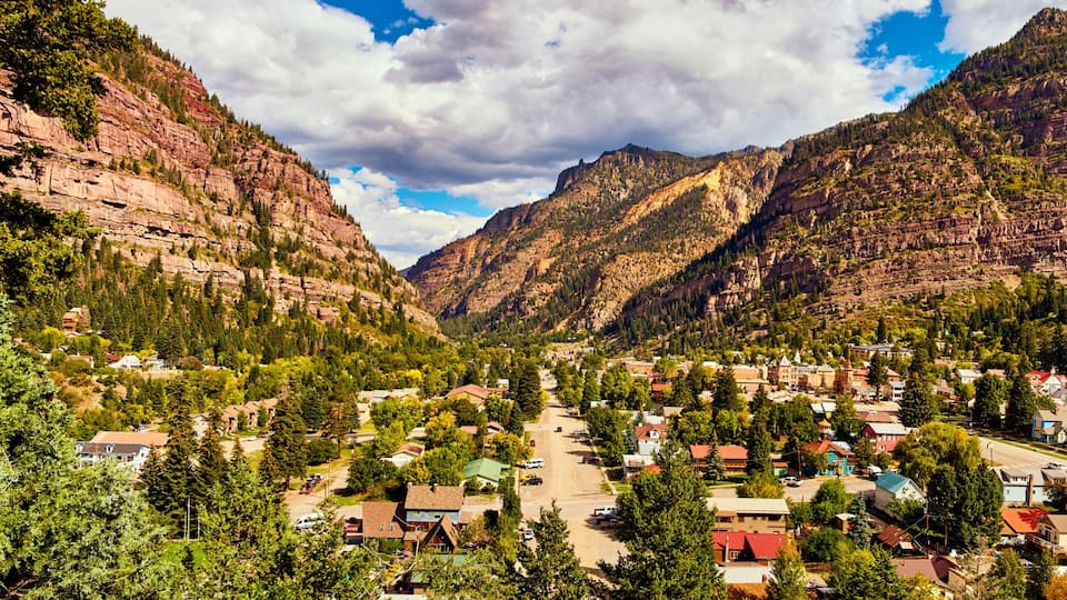 A valley town nestled between steep, forested mountains.