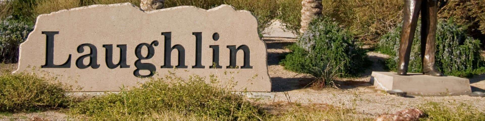 Visit to Laughlin Nevada showcases the iconic welcoming sign and statue amid palm trees