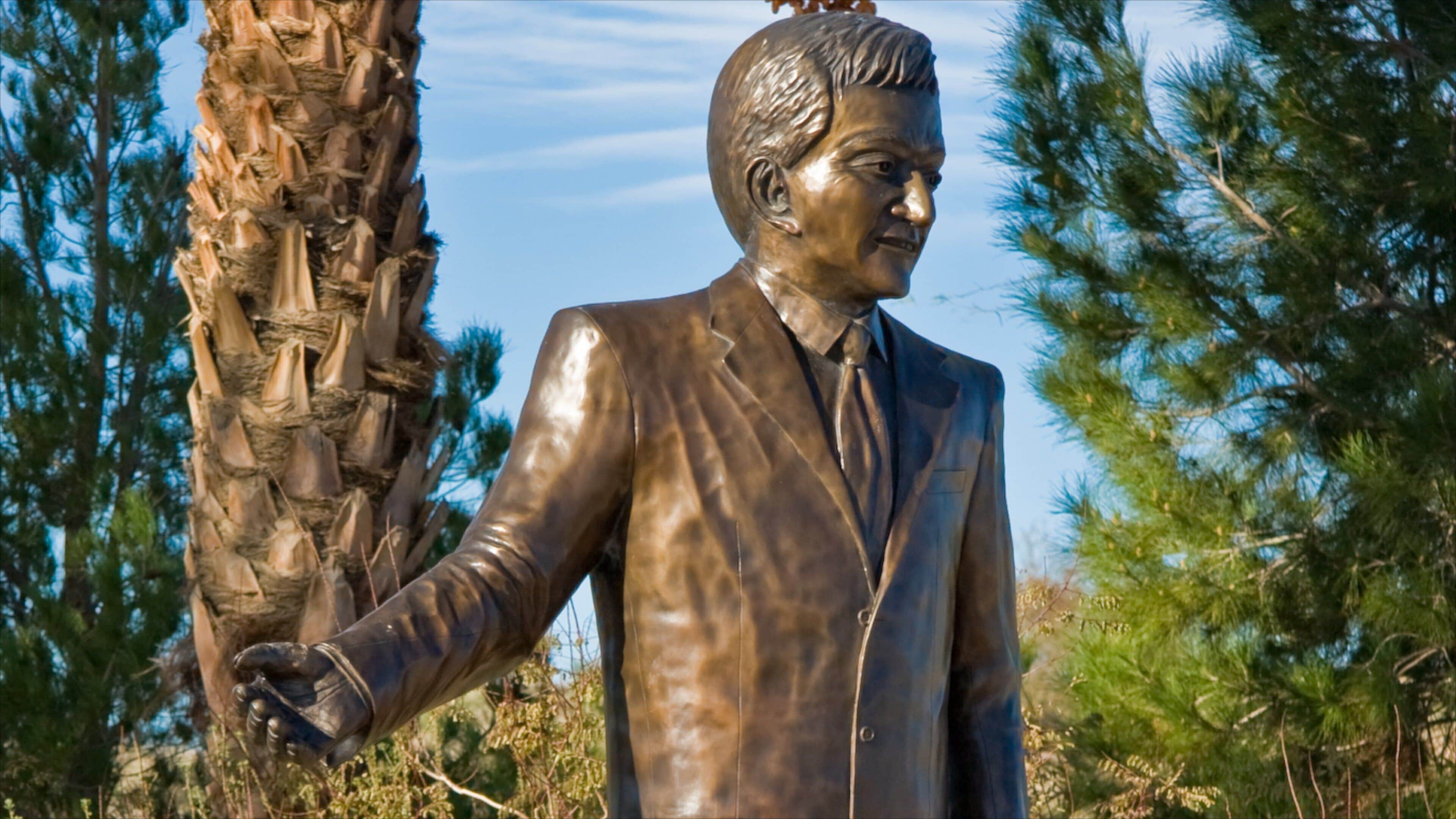 Statue of a notable figure in Laughlin, Nevada surrounded by vibrant palm trees and greenery