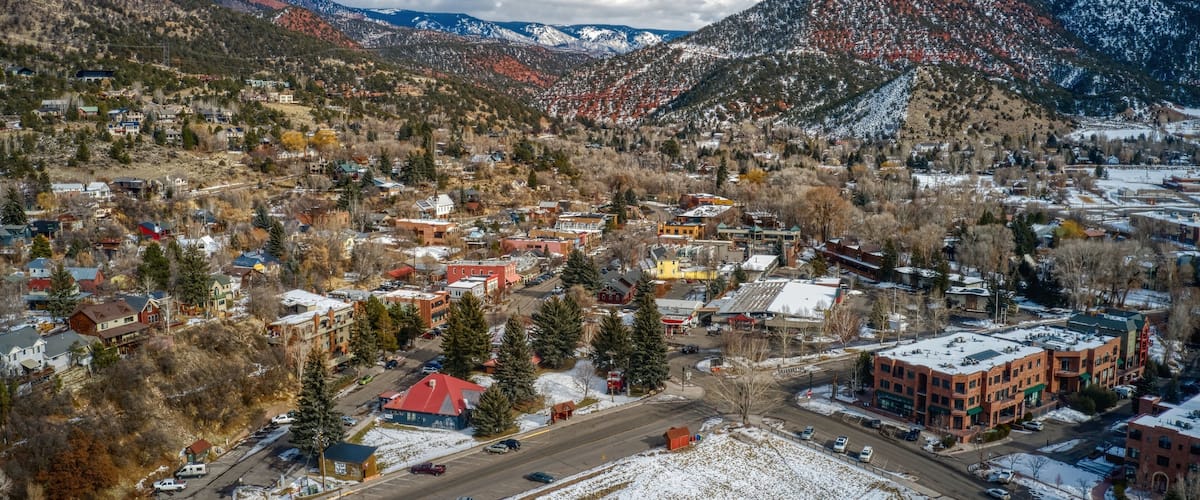 A town nestled in a valley with snow-covered mountains in the background.