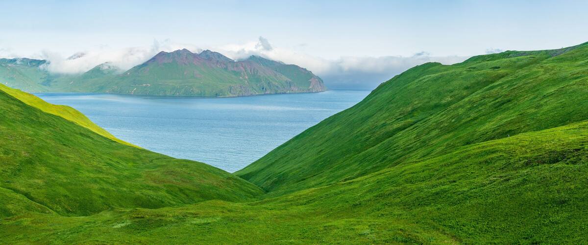 A green valley with a lake and a mountain in the background.
