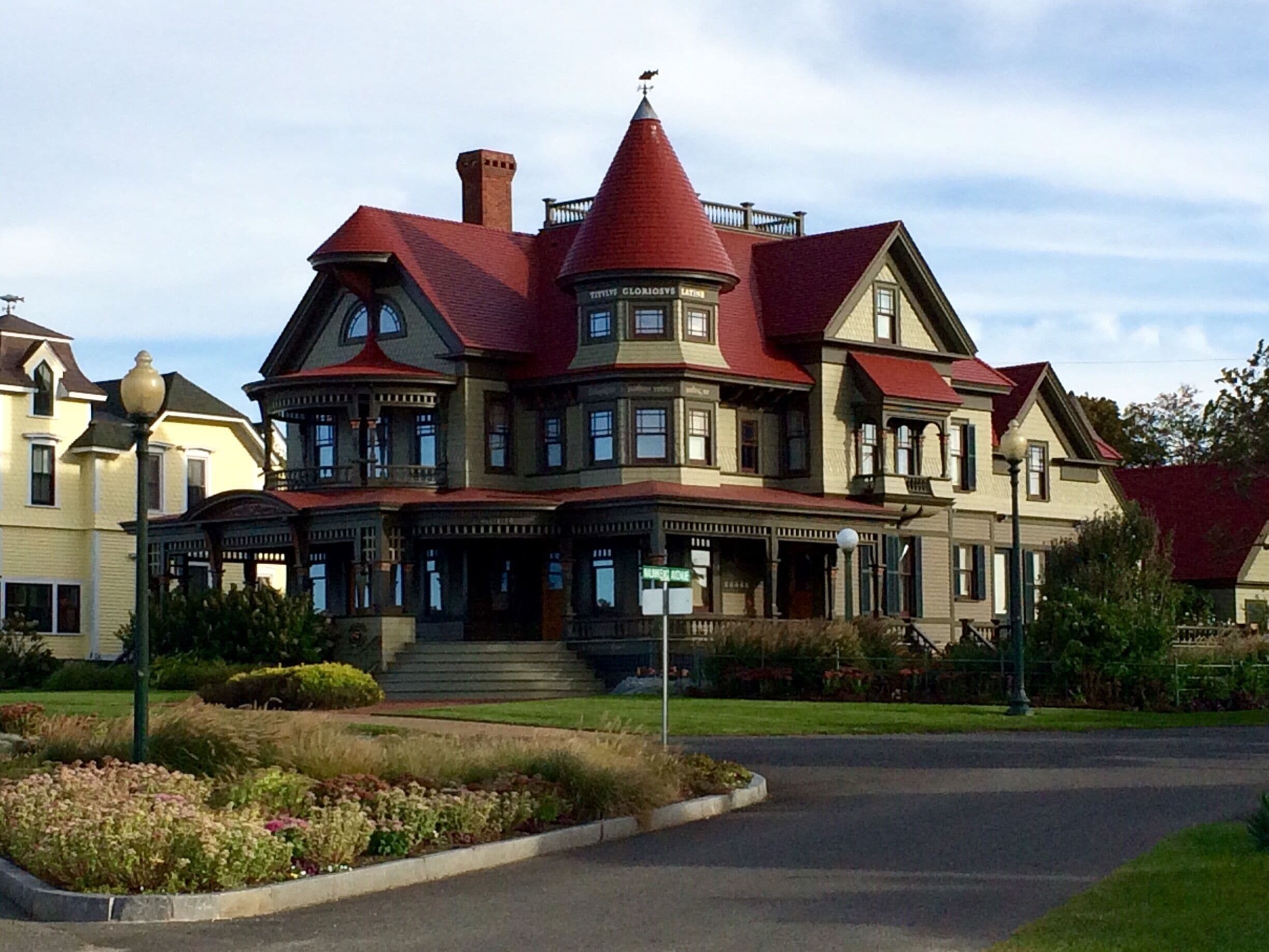 A large, Victorian-style house with a red roof and multiple chimneys.