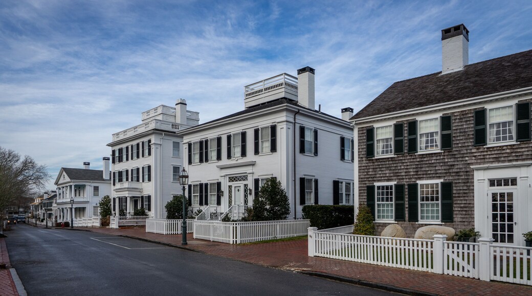 View of historic houses with white fences and black shutters along a quiet street on Martha's Vineyard in Edgartown, Massachusetts, United States.