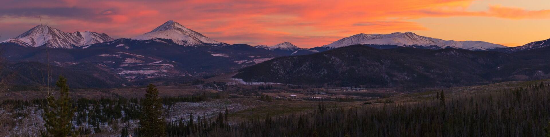 A mountain range with a valley in between, under a sunset sky.