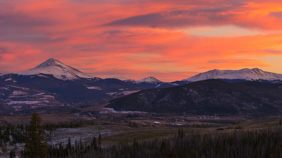 A mountain range with a valley in between, under a sunset sky.