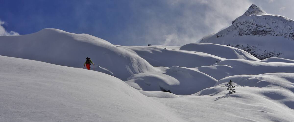 A snowy mountain landscape with a climber and a prominent peak.