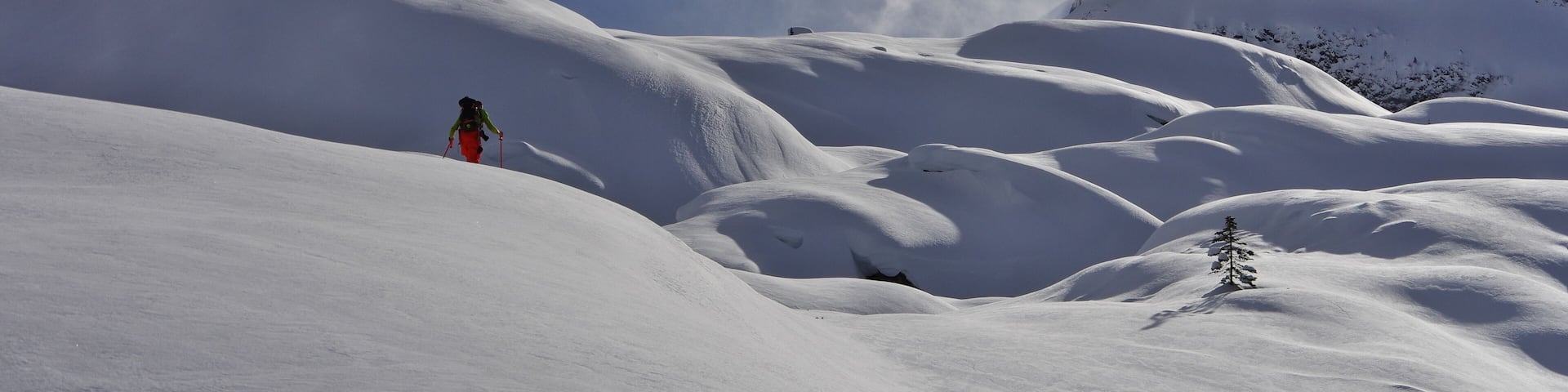 A snowy mountain landscape with a climber and a prominent peak.