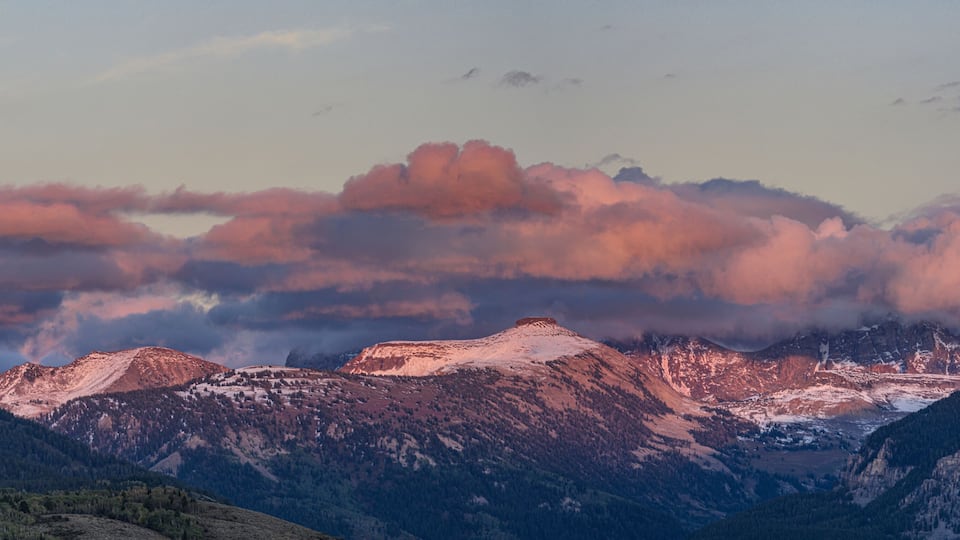 A mountain range with snow-capped peaks and a valley below.