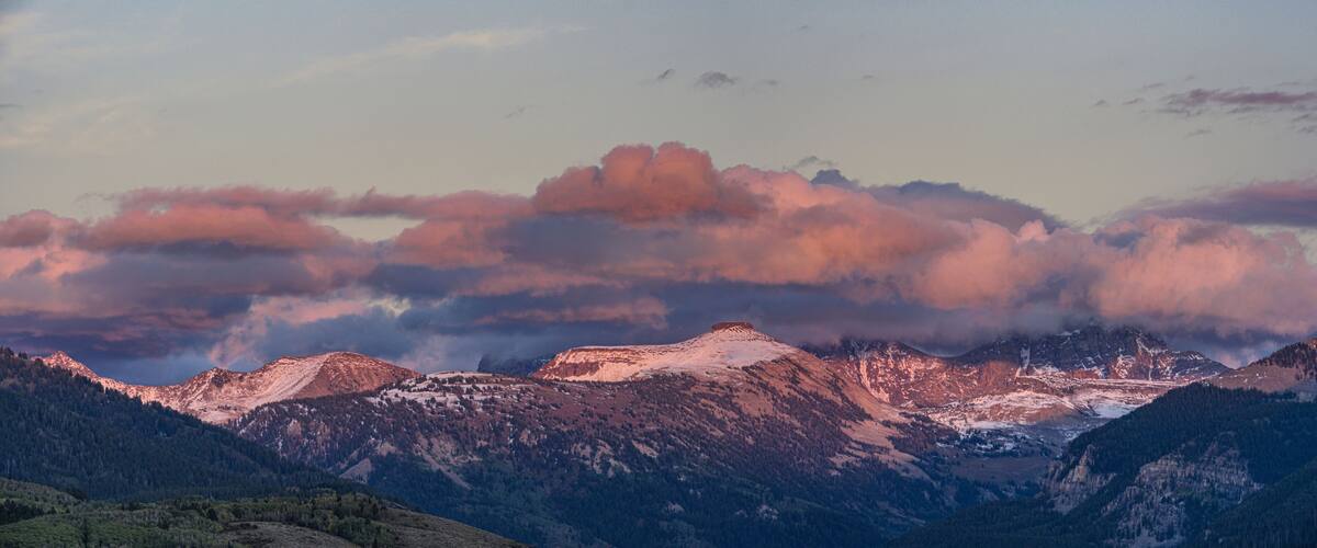 A mountain range with snow-capped peaks and a valley below.