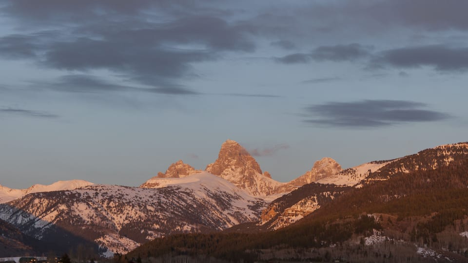 A mountainous landscape with snow-capped peaks and a clear sky.