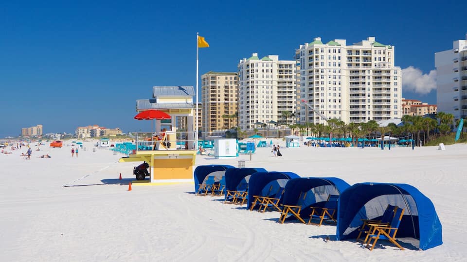A beach with tents, a lifeguard tower, and high-rise buildings in the background.