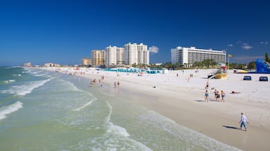 A beach with people, a lifeguard tower, and tall buildings in the background.