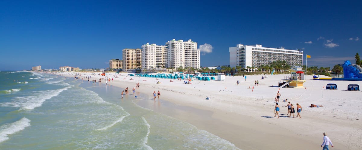A beach with people, a lifeguard tower, and tall buildings in the background.
