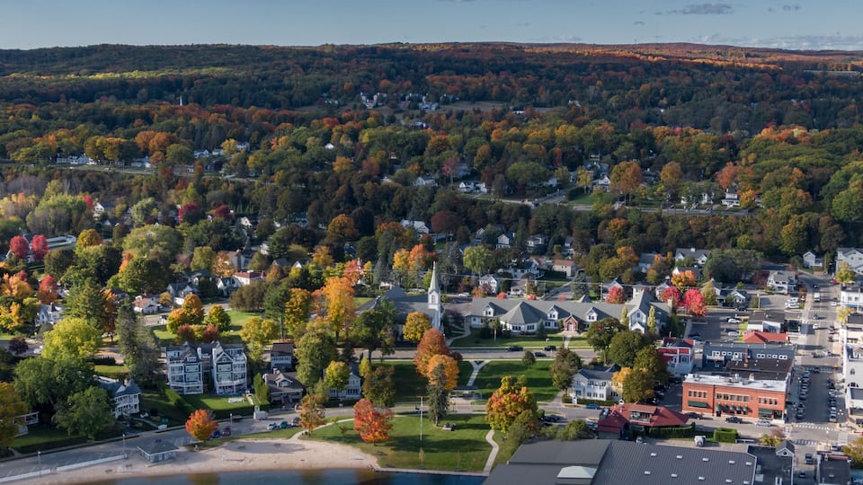 A coastal town with autumn foliage, a church, and a beach.