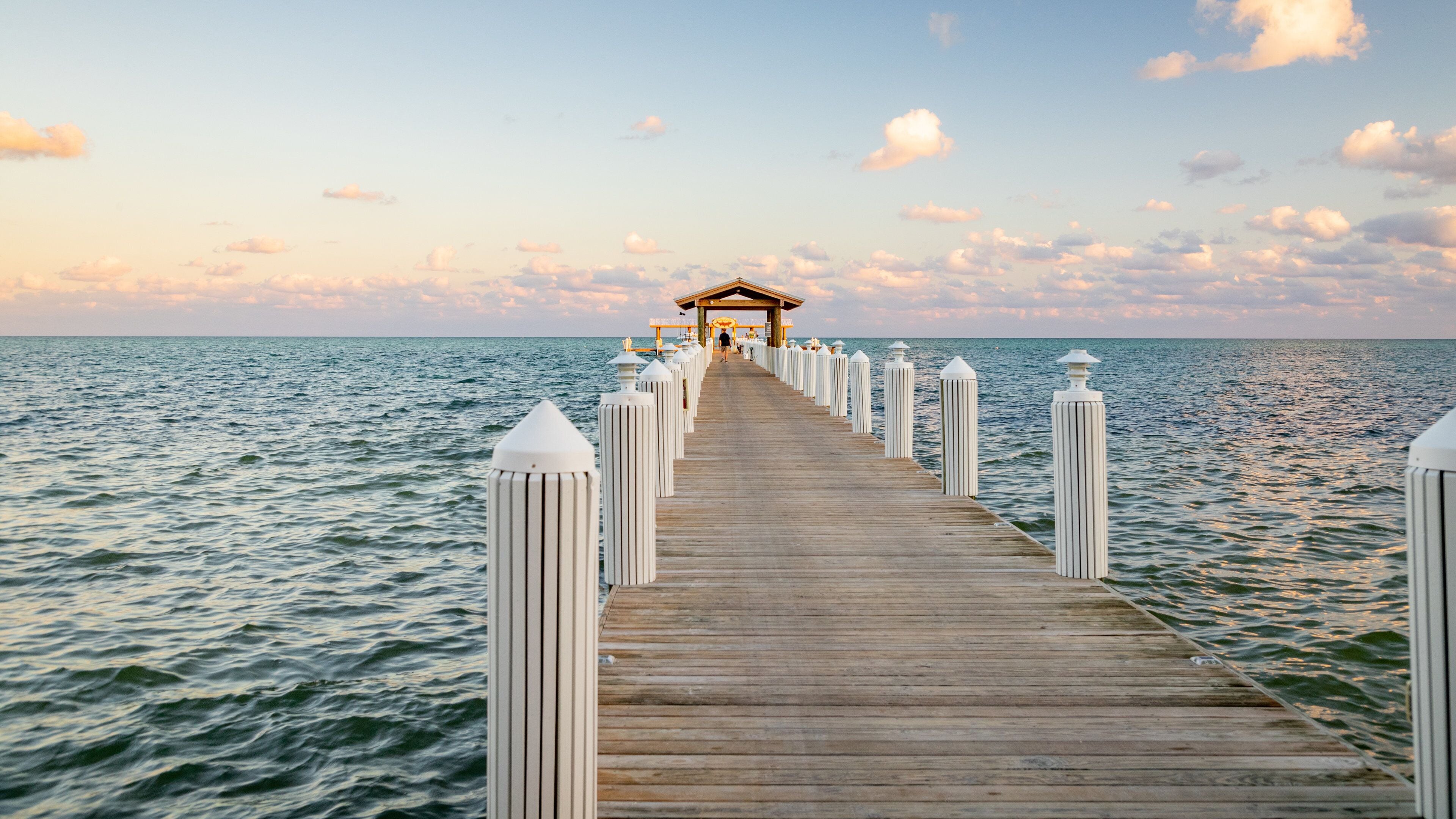 A wooden pier extending into the sea with a gazebo at the end.