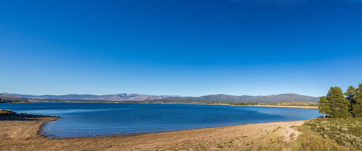 A large lake with clear blue water, surrounded by mountains and sparse vegetation.