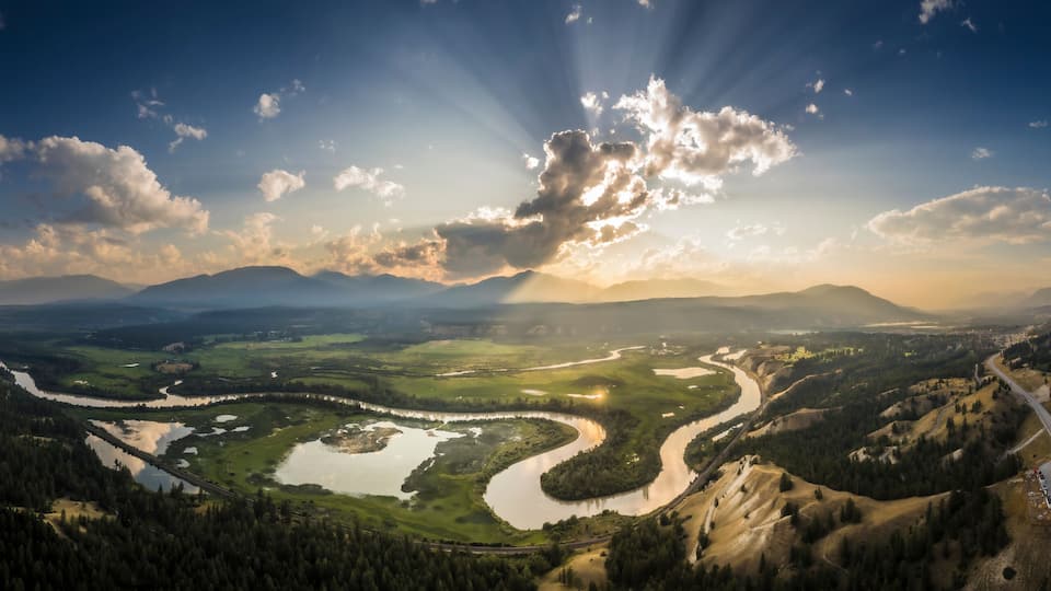 A river winding through a mountainous landscape with a bridge and a road.