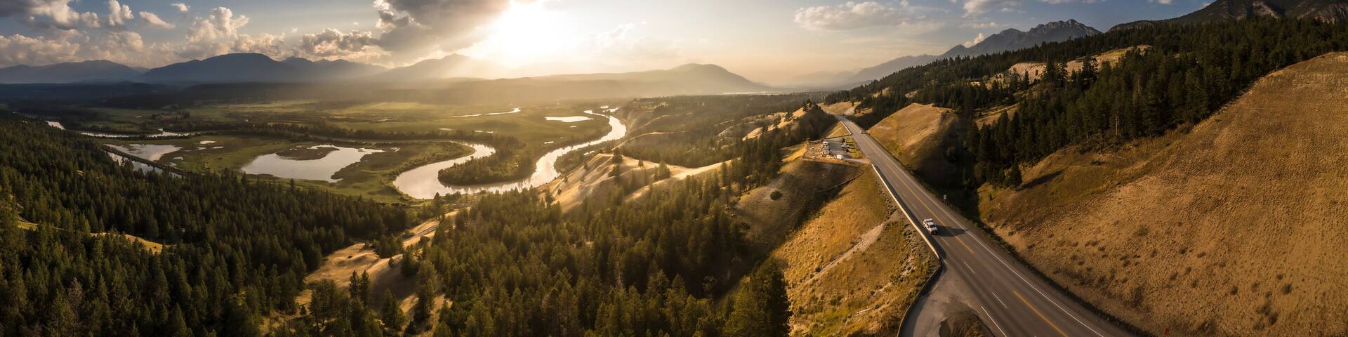 Aerial view of a tranquil sunset over the expansive wetlands and winding Columbia River surrounded by majestic mountains and serene forests, Invermere, Canada.